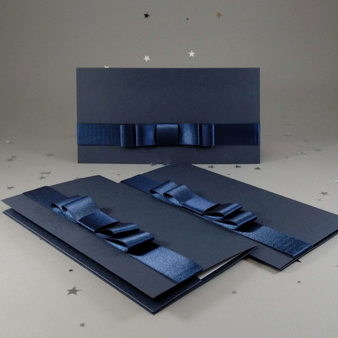 Dárková kapsa DL formátu z matného, mírně strukturovaného, tmavě modrého papíru, s aplikací z široké atlasové stuhy, celkový rozměr 206 × 106 mm.