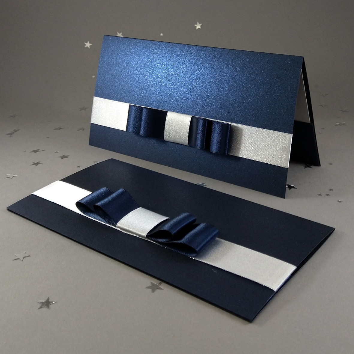 Dárková kapsa DL formátu z metalického, perleťového, tmavě modrého papíru, s aplikací z široké atlasové stuhy, celkový rozměr 206 × 106 mm.