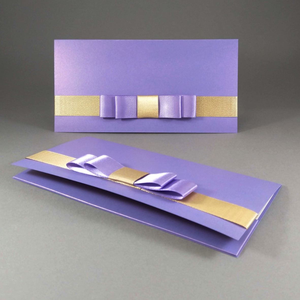 Dárková kapsa DL formátu z metalického, perleťového, fialového papíru, s aplikací z široké atlasové stuhy, celkový rozměr 206 × 106 mm.