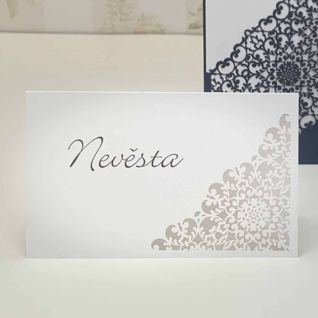 Jmenovka – bílá, na perleťovém papíře, motiv ornamentů je vytvořen jemným digitálním výsekem, 91 × 60 mm, jednostranná