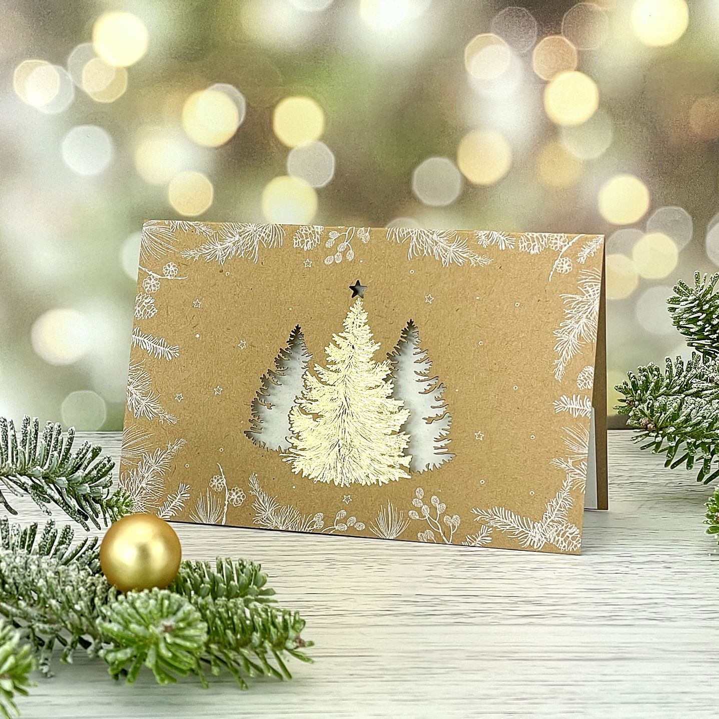 Novoroční–vánoční přání vyrobené z recyklovaného papíru s motivem trojice stromů provedených kombinací zlaté ražby a laserového výseku, otevírací, formát 148 × 105 mm.