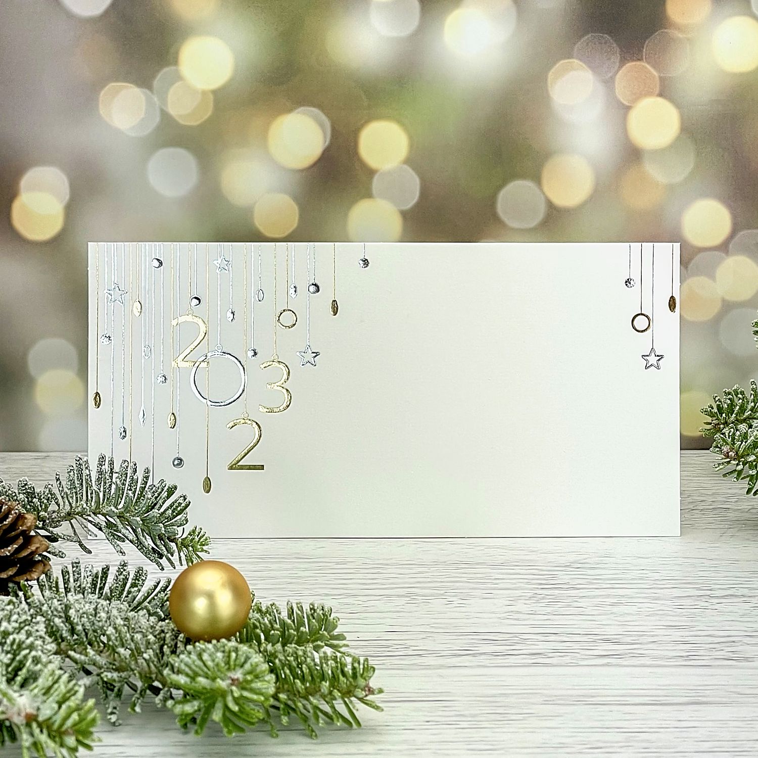 Novoroční–vánoční přání, jednoduchá karta s motivem závěsů z číslic letopočtu 2022 a vánočních ozdob, formát 200 × 100 mm.