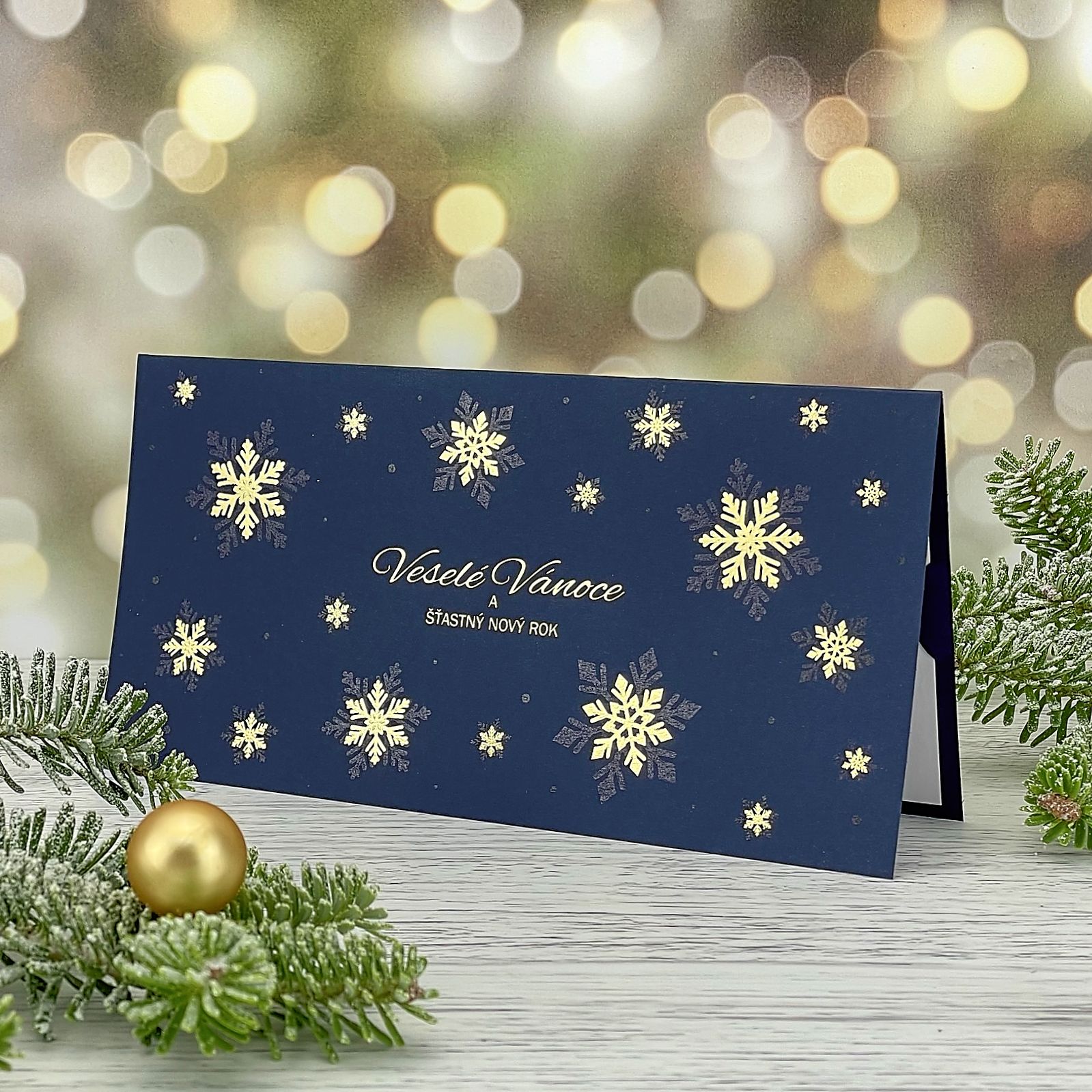 Novoroční–vánoční přání s motivem zlatých sněhových vloček, tmavě modrý grafický papír, otevírací, formát 200 × 100 mm.