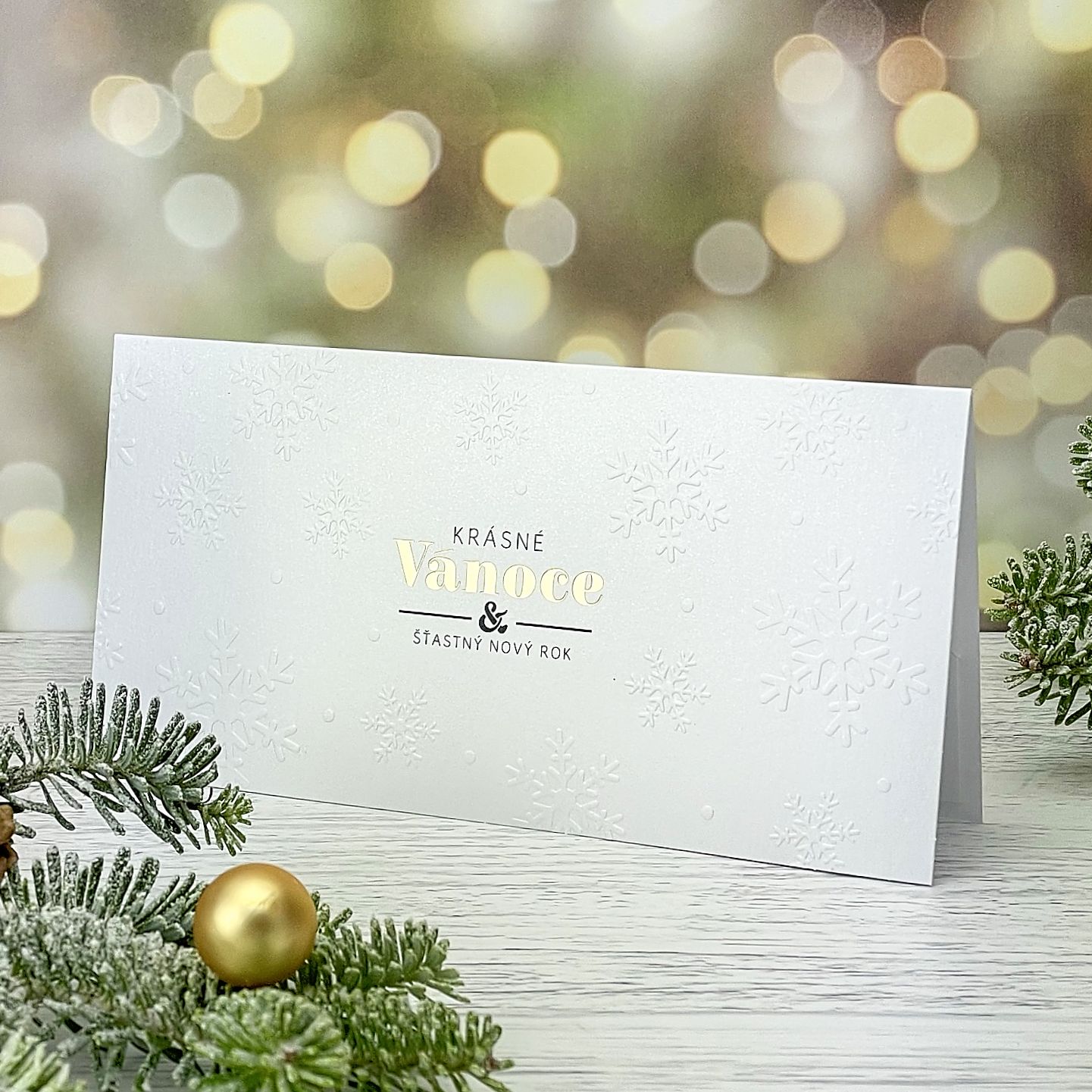 Novoroční–vánoční přání - elegantní, jednoduché, nadčasové, s motivem sněhových vloček vytvořených slepotiskem, perleťově bílý papír, otevírací, DL formát 200 × 100 mm.