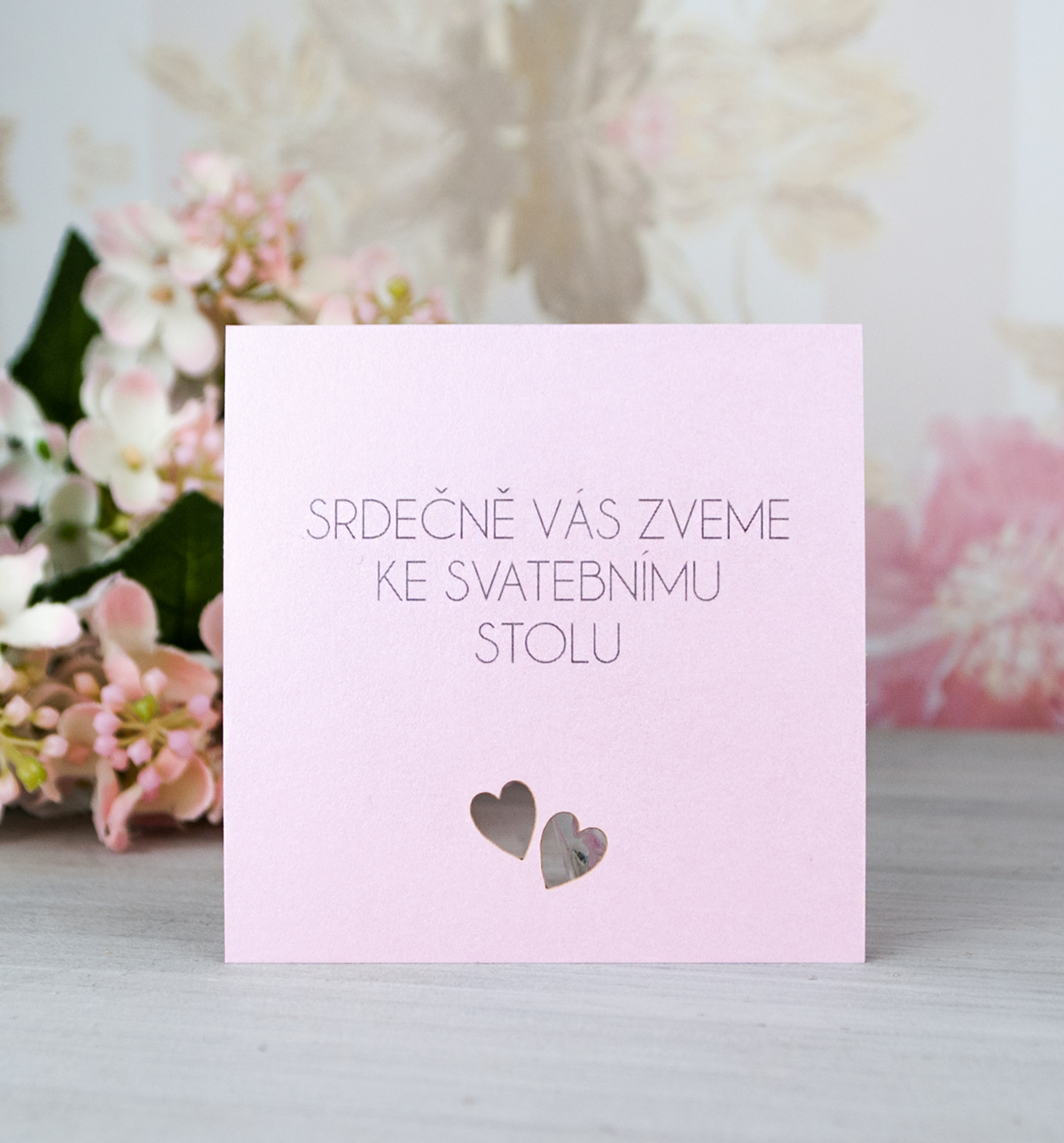 Pozvánka, informační karta – ze stříbrného a růžového perleťového papíru s jemným srdíčkovým motivem, 70 × 70  mm, jednostranná.