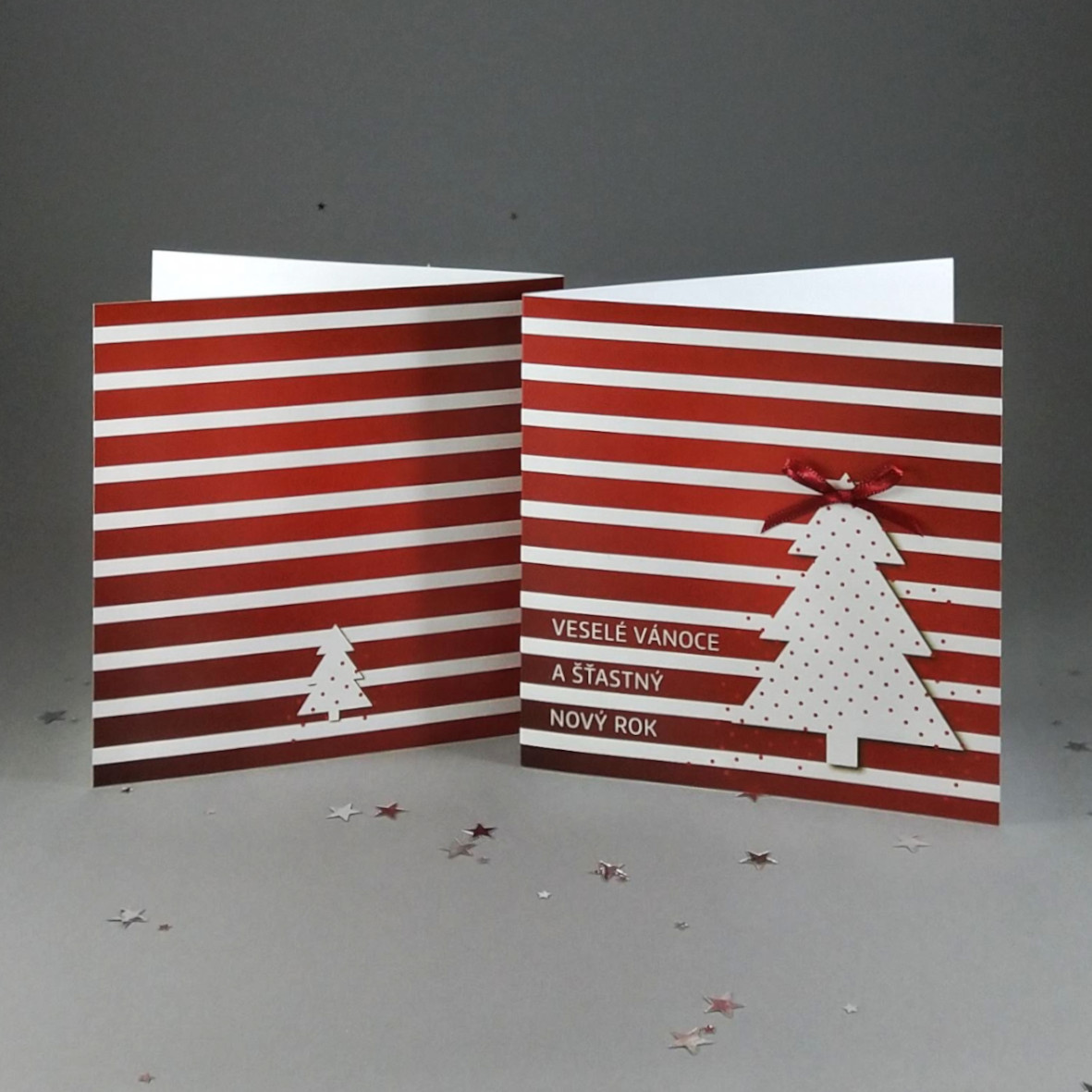 Novoroční – vánoční přání, s motivem vánočního stromečku s mašličkou na červeně pruhovaném pozadí, otevírací, formát 140 × 140 mm, digitální tisk, bílý perleťový papír.