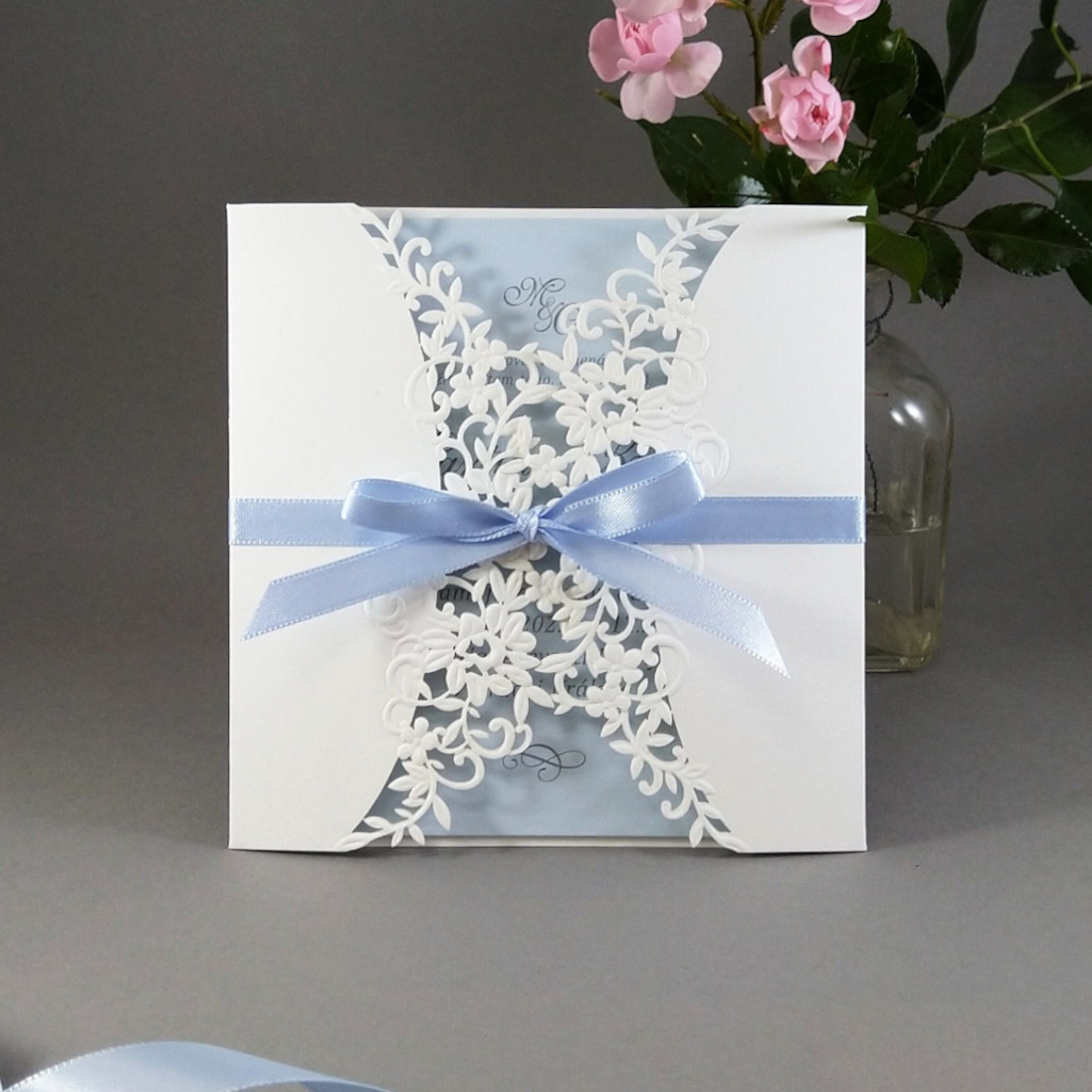 Svatební oznámení – čtvercové s krajkovým přebalem se světle modrou vnitřní kartou a atlasovou stuhou.