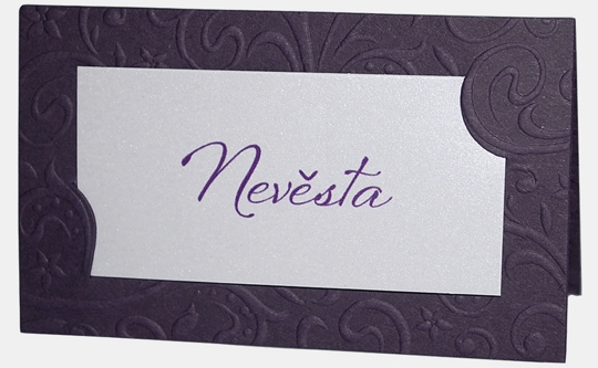 Jmenovka – z fialového grafického papíru je orámována slepotiskovým ornamentem. Uprostřed je do zámečků vložena bílá kartička s textem, 90 × 54 mm, jednostranná